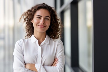 portrait of successful business woman in white shirt  standing with arms crossed in the office