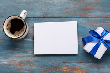 Beautiful Christmas composition with mug of coffee, blank card and gift box on blue wooden...