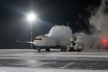 Ground deicing of a passenger airliner on the night airport apron at winter