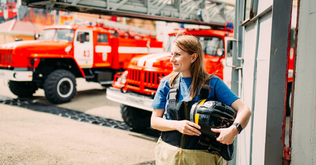 Female firefighter in protective uniform standing near red fire truck