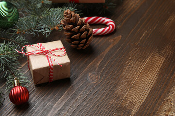 Beautiful fir branches with gift box and Christmas decorations on brown wooden background