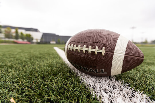 Close up view of an American Football sitting on a grass football field on the yard line. Generic Sports image 