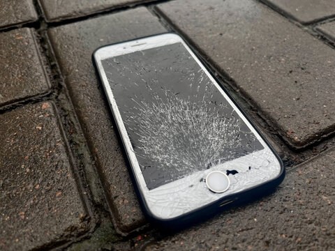 Broken glass screen smartphone Apple Iphone 7. A broken iPhone is lying on the road.