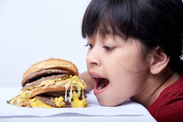 Cute little girl eating an appetizing cheeseburger