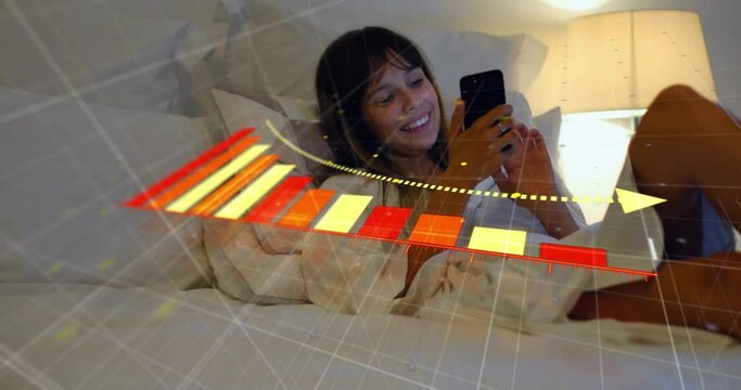 Animation of arrow on falling graph, smiling biracial woman lying on bed and scrolling on cellphone