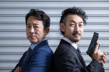 カッコイイビジネスマンや刑事ドラマや映画ののバディのイメージ　シャッターの前に立つ　クローズアップ © kapinon