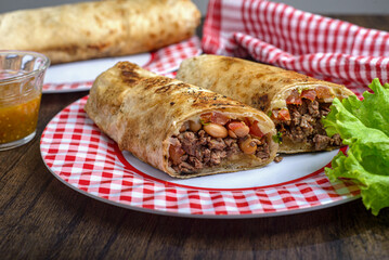 Burrito on a plate on a wooden table. Typical mexican food.