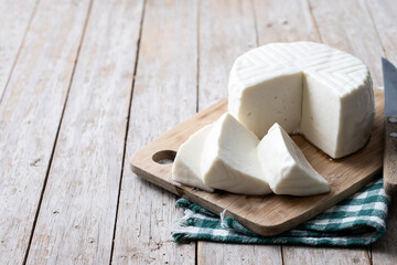 Sliced fresh white cheese from cow's milk on wooden table. Copy space