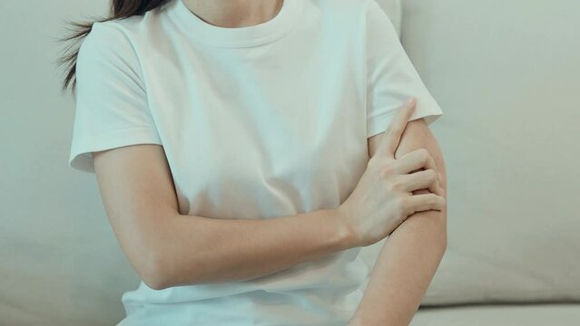 Woman having arm pain during sitting on couch at home, muscle injury and ache. Health and medical concept
