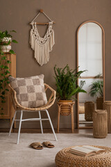 Creative composition of bedroom interior with mirror, chess board print pillow, plaid, plants in flowerpots, macrame, rattan sideboard, brown wall and personal accessories. Home decor. Template.