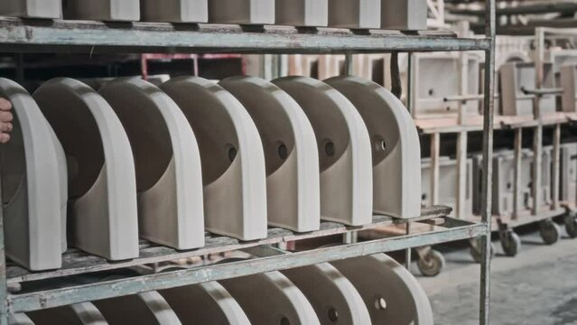 Sink blanks are stacked on a rack-cart in a plumbing production facility. Stage of production of ceramic sanitary ware at the enterprise.