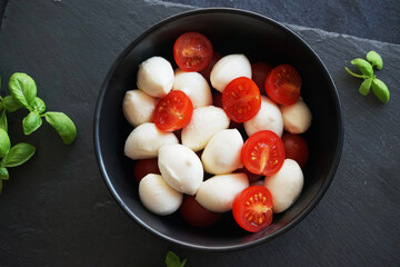 Mozzarella with cherry tomatoes with basil on a dark gray background