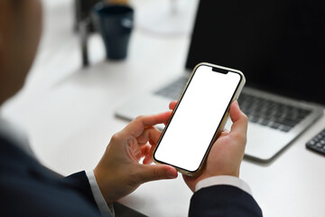 Over shoulder view of male manager using smartphone at desk