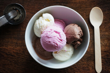 Ice cream scoops in a white plate with a wooden spoon on a wooden board
