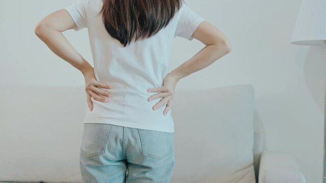 woman having back body ache during sitting on Couch at home. adult female with muscle pain due to Piriformis Syndrome, Low Back Pain and Spinal Compression. Office syndrome and medical concept
