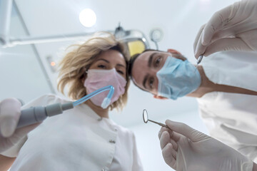 Two dentists in face masks and rubber gloves, low angle shot