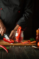 Chef preparing fresh vegetables in the kitchen. The cook cuts fresh peppers on a wooden cutting board. Healthy or vegetarian food concept