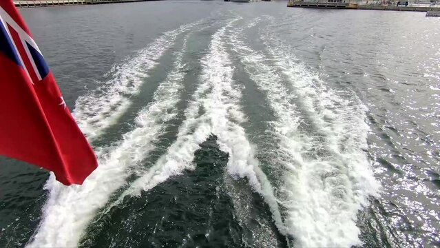 Departing Hobart wharf showing the engine wash and flag on a tourist boat travelling to the museum at Mona