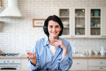 Smiling woman in headset talking with client by video call