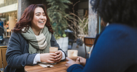 Young multiracial women having coffee break at vintage bar outdoor during winter time - Cozy...
