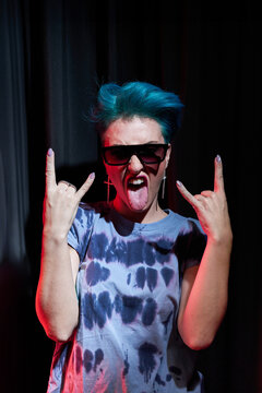Excited young female showing rock n roll gesture and looking at camera