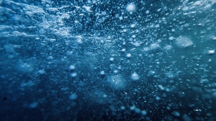 Obraz premium Underwater view on fast water stream with flowing air bubbles rising up to the sea surface