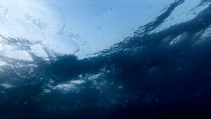 View from the sea bottom on water ripples and rising air bubbles under the sea water surface