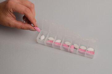 Close-up of unrecognizable girl sorting vitamins into pill organizer , biohacking concept