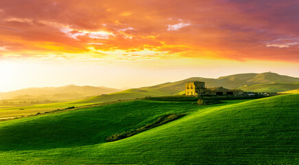 amazing sunset among green spring hills in highland farm with castle , mountains and picturesque colorful sunset on background of landscape