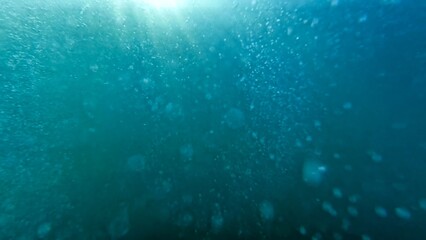 Air bubbles rising from the sea bottom up to water surface. Diver releasing air. Abstract natural background or backdrop