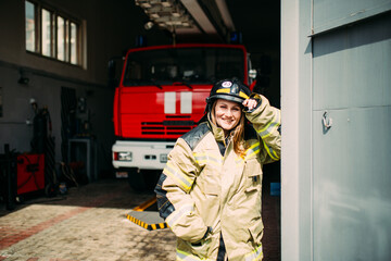 Female firefighter in protective uniform standing near red fire truck