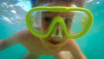 Little boy wearing snorkeling mask swimming underwater and exploring ocean marine world. Concept of...