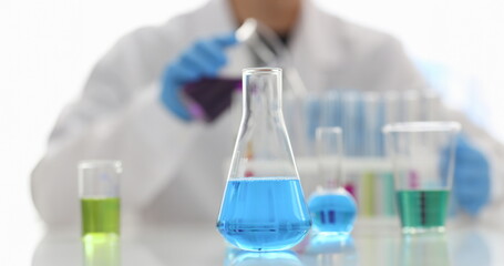 A male chemist holds test tube of glass in his hand overflows a liquid solution of potassium permanganate. Conducts an analysis reaction takes various versions of reagents using chemical manufacturing