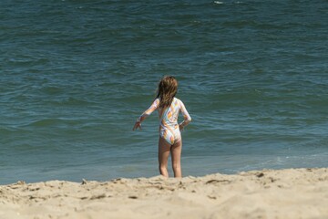 a young girl on the beach playing with a frisbee