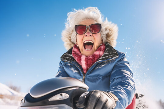 happy crazy smiling old woman on snowmobile in snowy winter outdoors