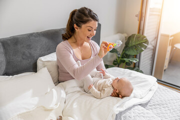 Mother with baby on the bed in the morning,enjoying in their morning routine