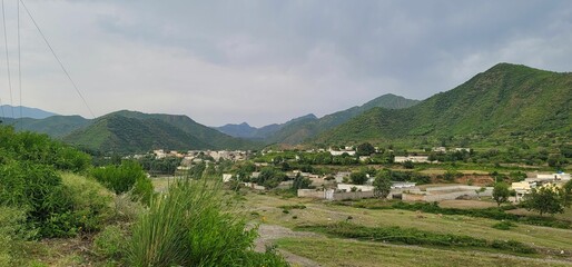 Scenic view of a small town surrounded by majestic mountain ranges and lush greenery