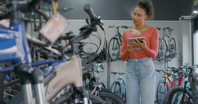 Female Small Business Owner Working in Bicycle Store using Digital tablet