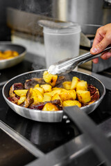Chef cook hand cooking potato and meat food in pan at the restaurant kitchen