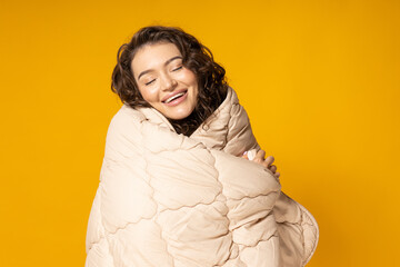 The girl is wrapped in a blanket on a yellow background.
