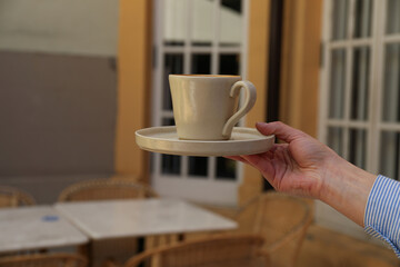 Cup in hand in outdoor cafe, close up