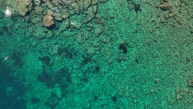 Il mare della Sicilia, Italia. Acqua azzurra, trasparente e cristtallina.
Vista dall'alto verticale del fondale marino, con scogli e sassi della lava dell'Etna. Clip ideale per titoli e testi.