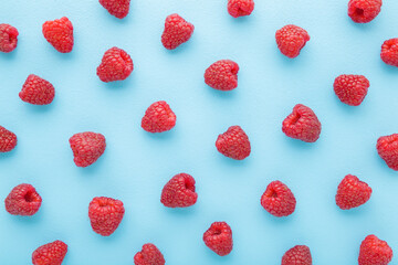 Fresh red raspberries on light blue table background. Pastel color. Berries pattern. Closeup. Top...
