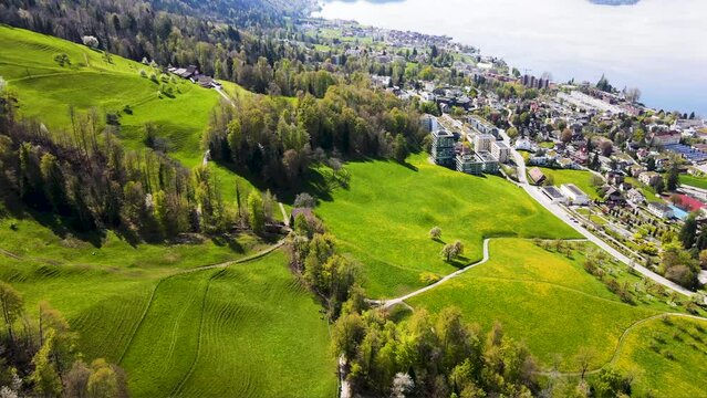 Cinematic aerial view of Idyllic Swiss lake and Swiss urban landscape in the Swiss Alps featuring lush green alpine meadows, lake surface reflections, Zugersee in Switzerland     