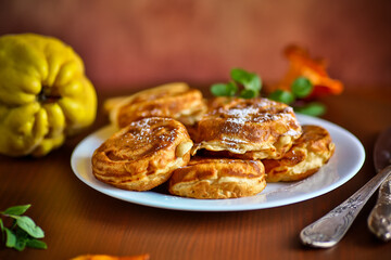 Obraz na płótnie Canvas Cooked fried round pancakes with quince filling on a wooden table