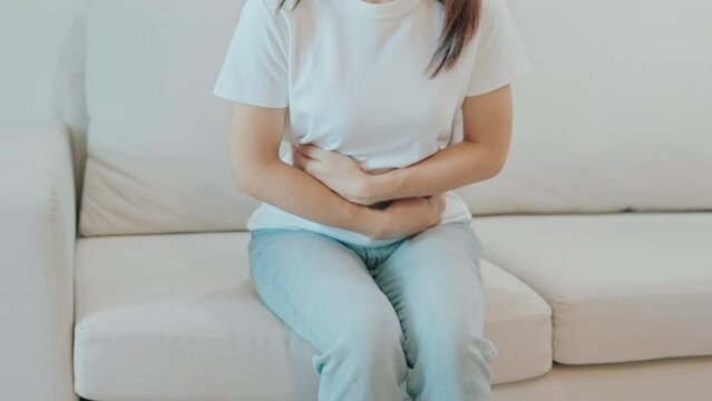 female problem and Endometriosis, Hysterectomy and Menstrual on the sofa at home, woman having abdomen ache due to Stomach pain, digestion with constipation or Diarrhea from food poisoning