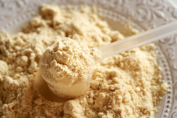 Whey protein powder in a measuring spoon on a plate