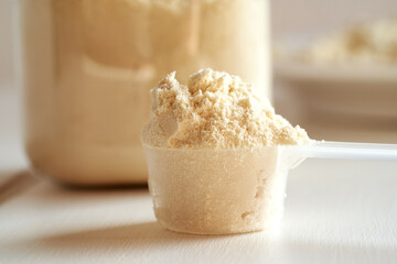 Whey protein powder in a scoop and in a jar