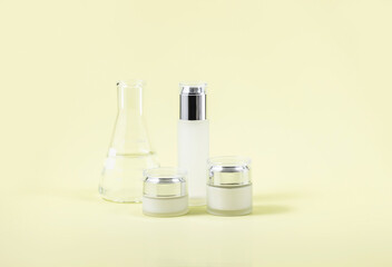 cosmetic containers and a laboratory flask on a yellow background