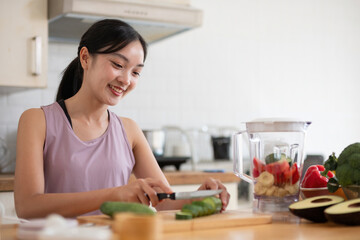 Young Asian healthy beautiful woman with casual clothes is smile and slicing fresh fruit to diet at home in kitchen in holiday